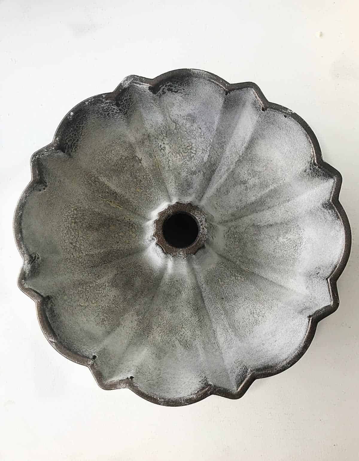 Top view of a large floured bundt pan on a white surface