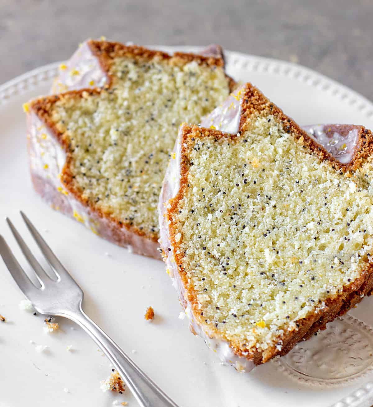 Two slices of lemon poppy seed bundt cake on white plate with fork