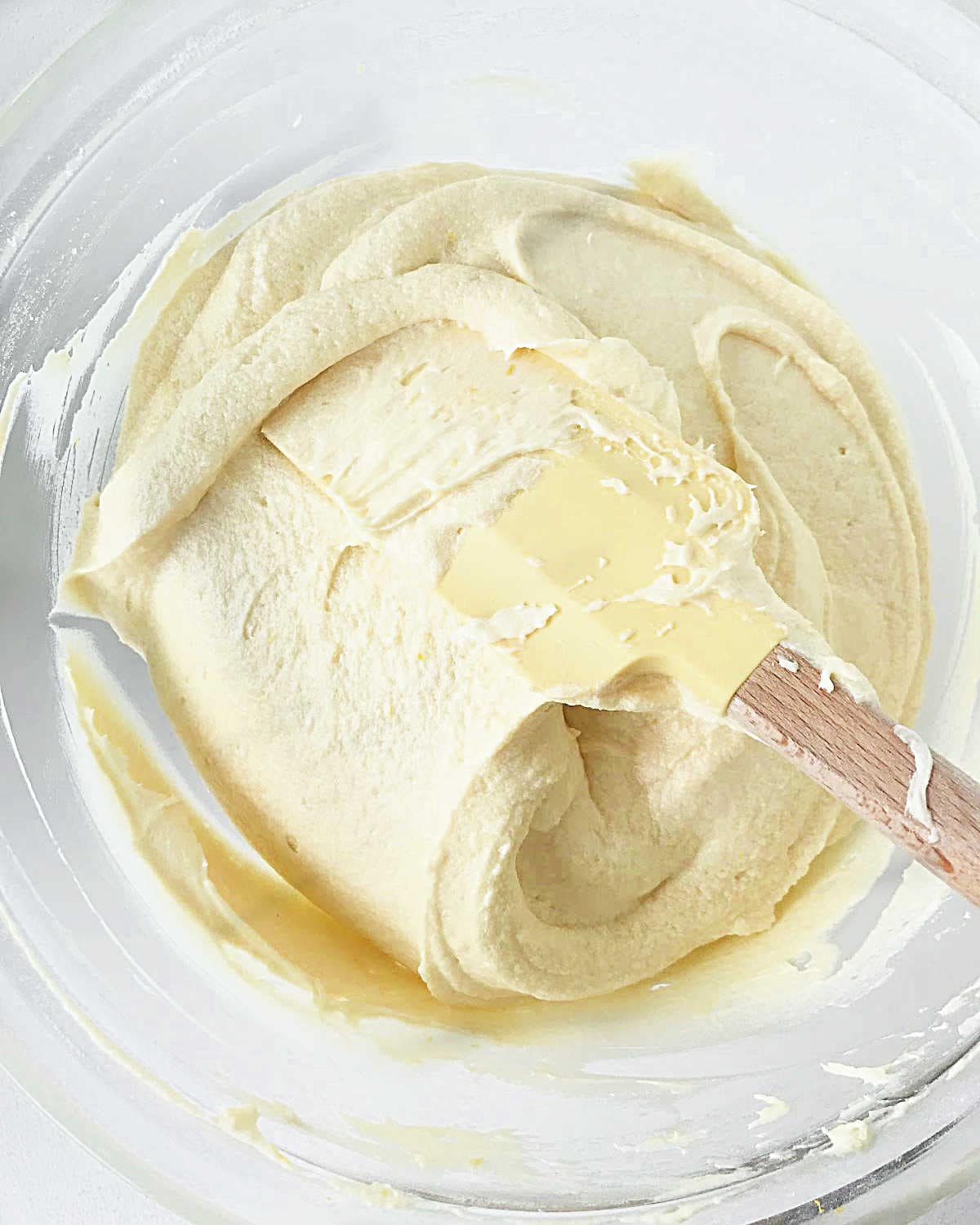 Glass bowl with lemon cake batter and a yellow spatula.