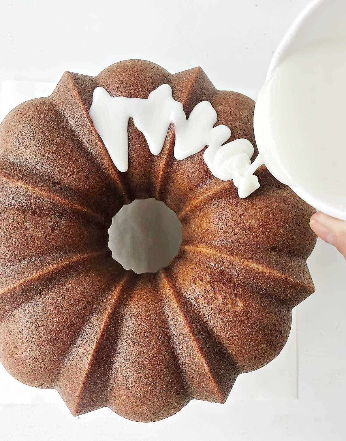 Pouring glaze over bundt cake. Top view. White surface.