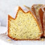 Cut lemon poppy seed bundt cake on a white plate with light grey background.