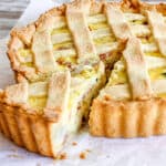 Whole lattice ricotta pie with one slice coming out on a white paper