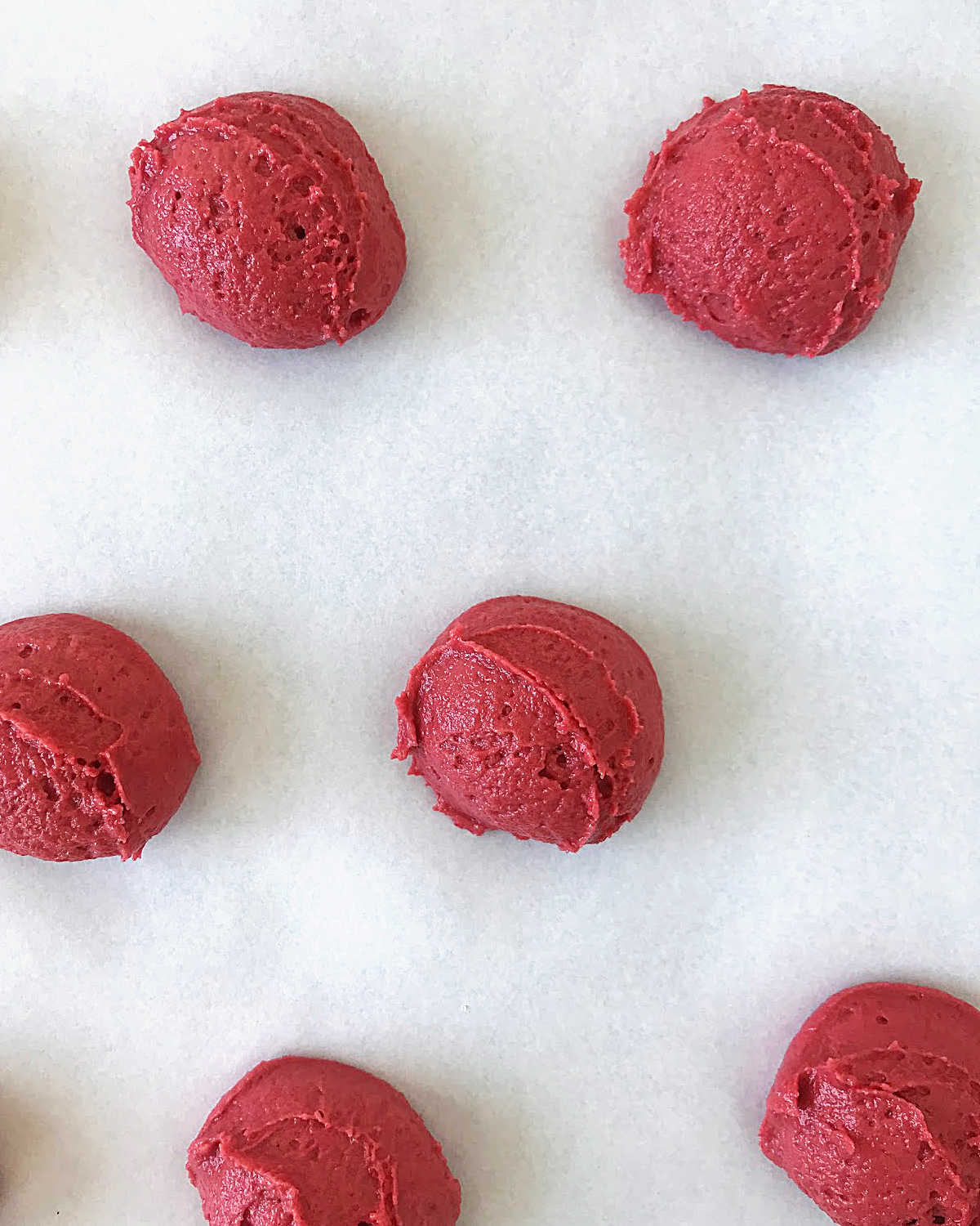 White parchment paper with mounds of red velvet whoopie pie batter.