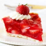 Single slice of strawberry jello pie on white plate with white background