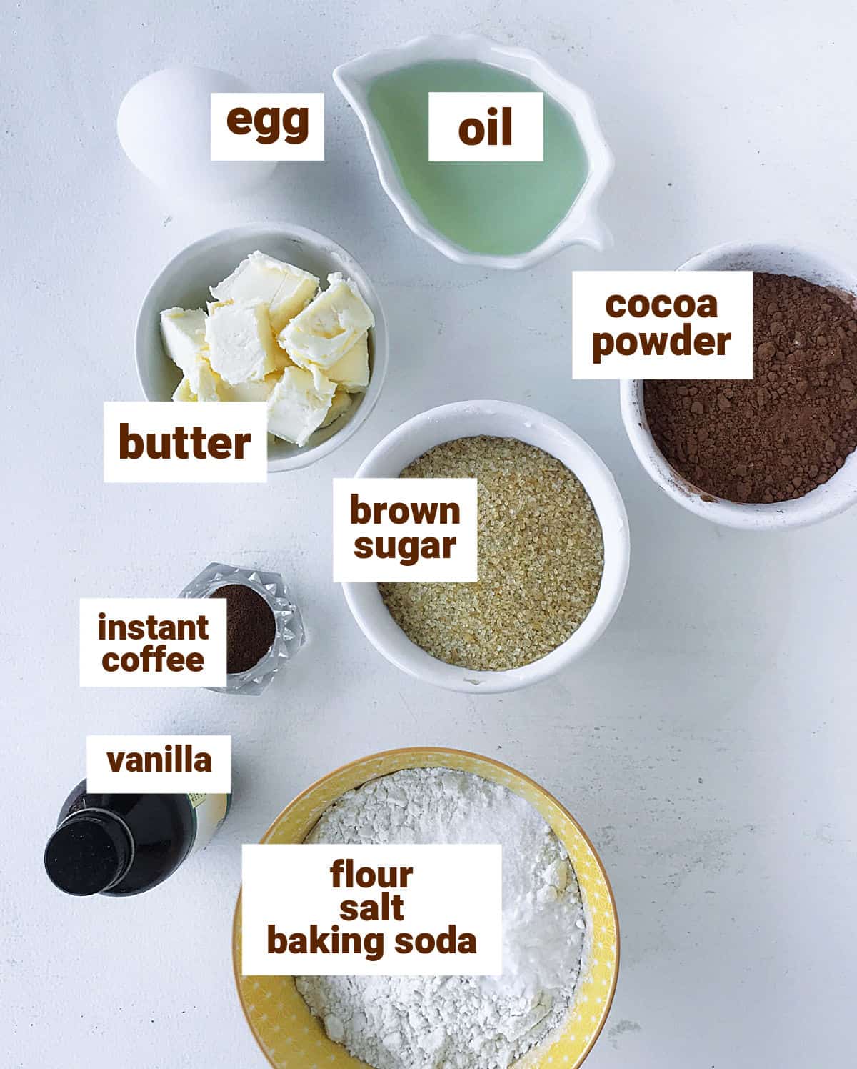 Different bowls with ingredients for chocolate whoopie pies, including egg, cocoa powder and vanilla; text overlay