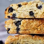 Close up of stack of blueberry scones with grey background; white text overlay