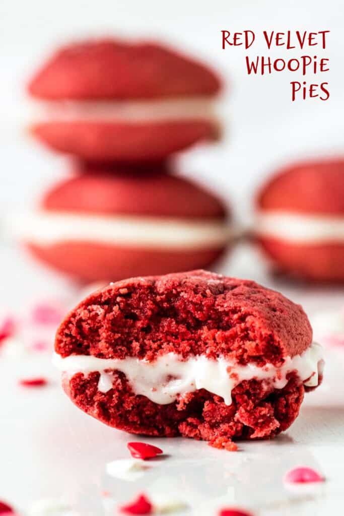One bitten red velvet whoopie pie on marble surface, stack of pies in background; red text overlay