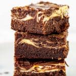 Three cheesecake brownies stacked with white background, brown text overlay