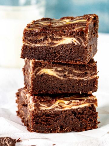 White and blue background with stack of cheesecake brownies.