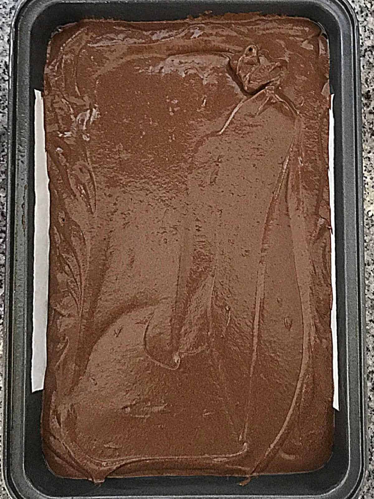 Top view of chocolate cake before baking in a metal rectangular pan.