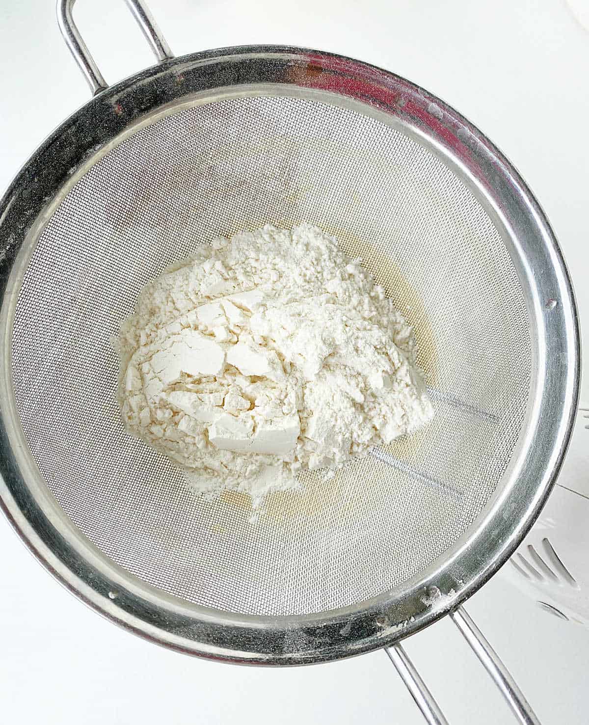 Sifter with flour on white surface