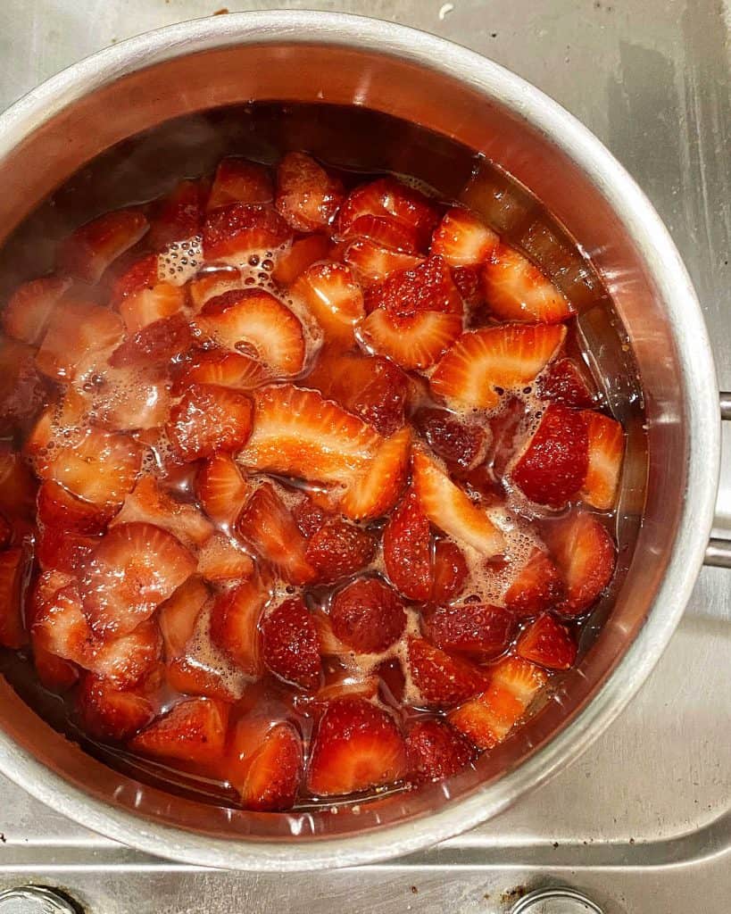 Metal saucepan with strawberry sauce in the making. Top view. 