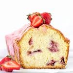 Front view of cut pound cake with strawberries and pink glaze; white background
