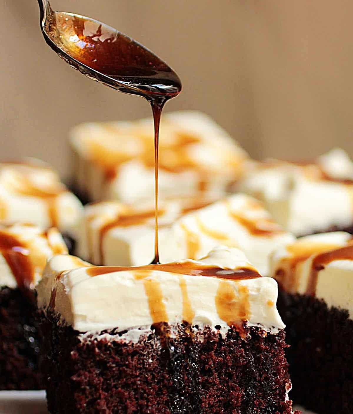 Spoon dripping stout syrup over cream topped chocolate cake
