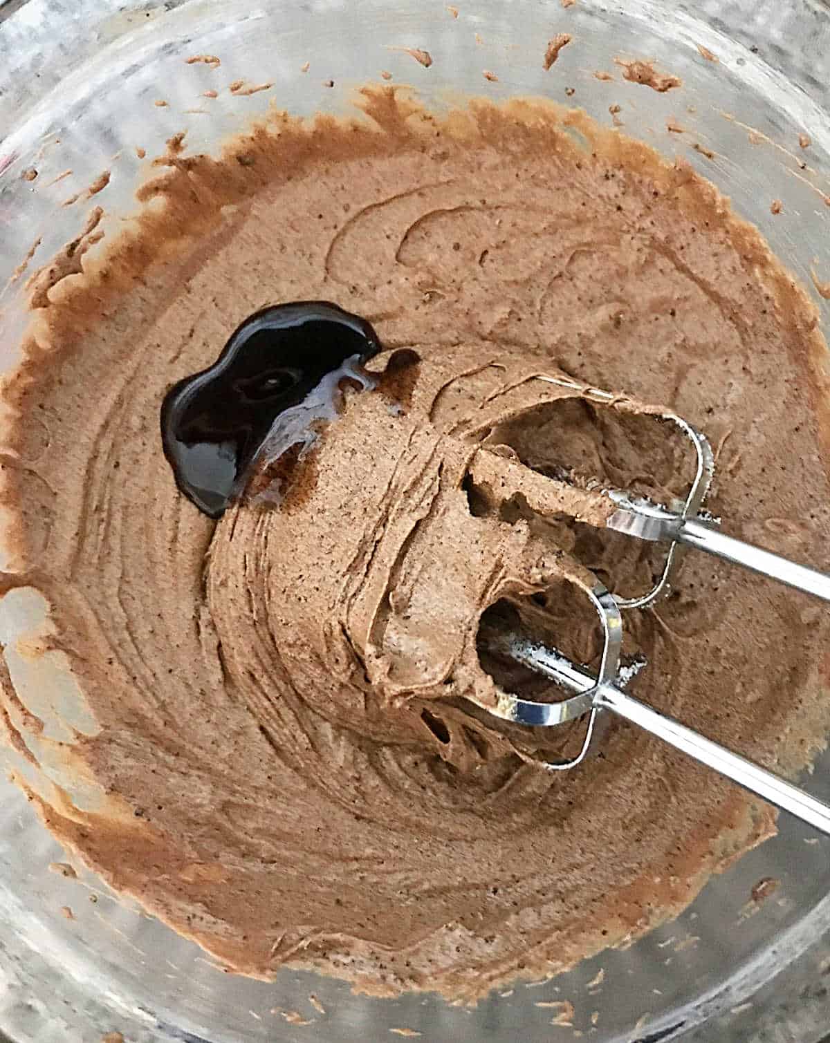 Top view of chocolate batter in bowl with metal beaters