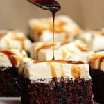 Stout syrup being poured over cream topped chocolate cake square