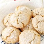 Several crackled almond cookies on white and blue kitchen towel; red text overlay