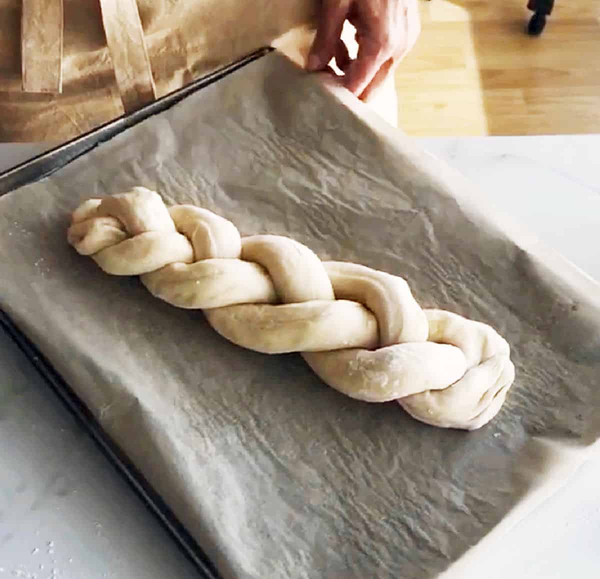 Unbaked braid of dough on a parchment lined pan.