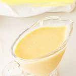 Glass jar with custard cream on white surface; yellow brown text overlay