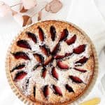 Top view of whole plum cake on white background; red text overlay