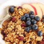 Close up of granola and fruit on white bowl; red text overlay