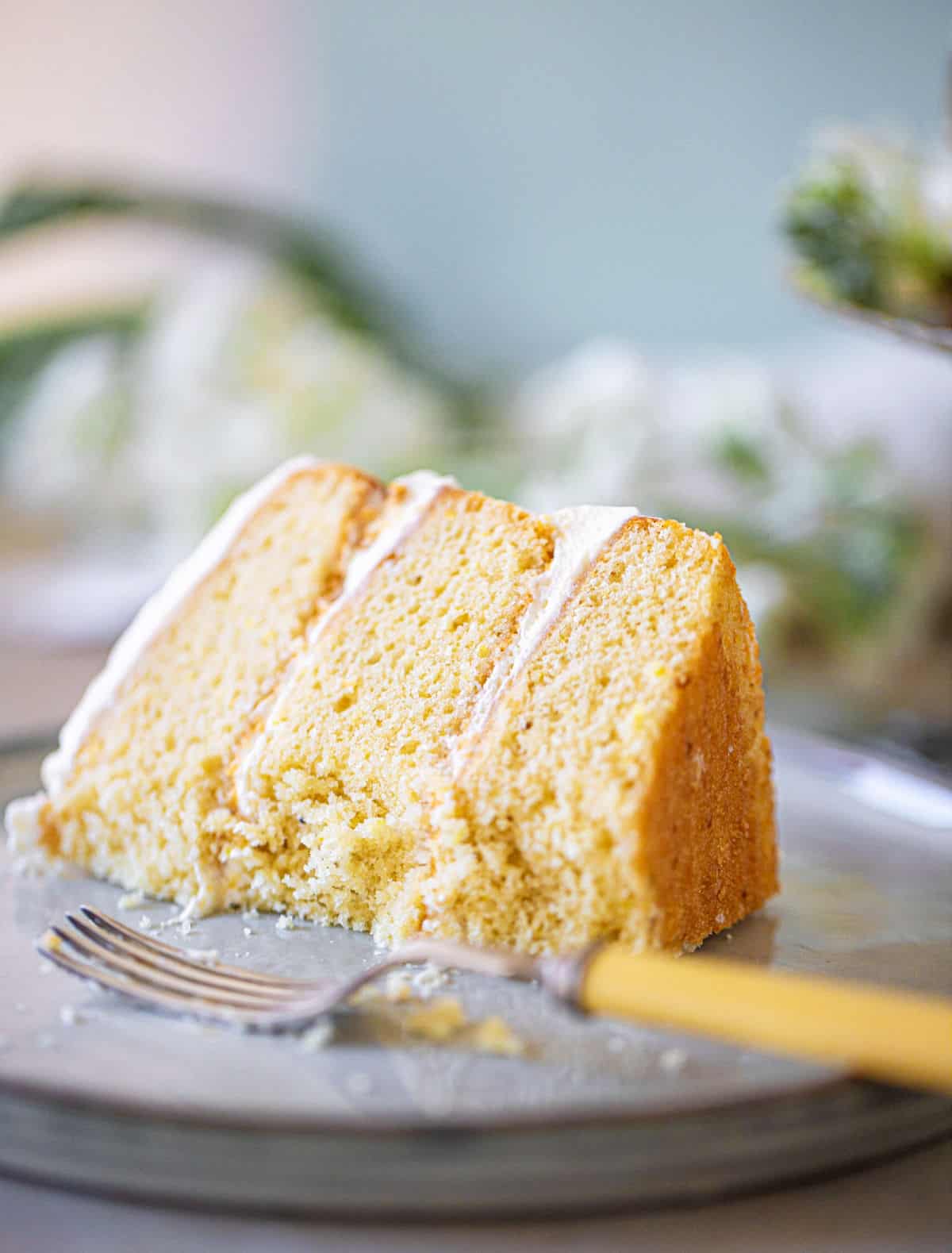 Eaten single slice of layer lemon cream cake with fork on grey plate