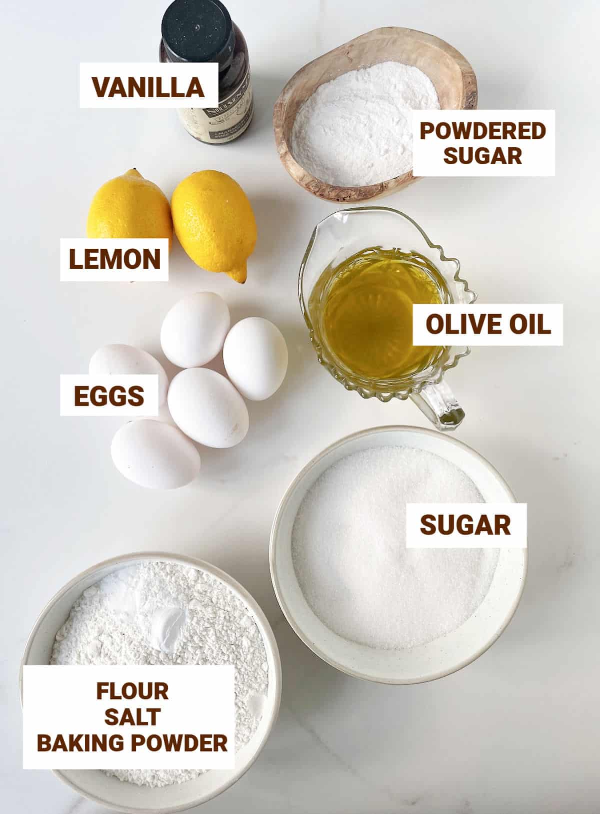 Ingredients for lemon olive oil cake in bowls including eggs, vanilla, flour, sugars.