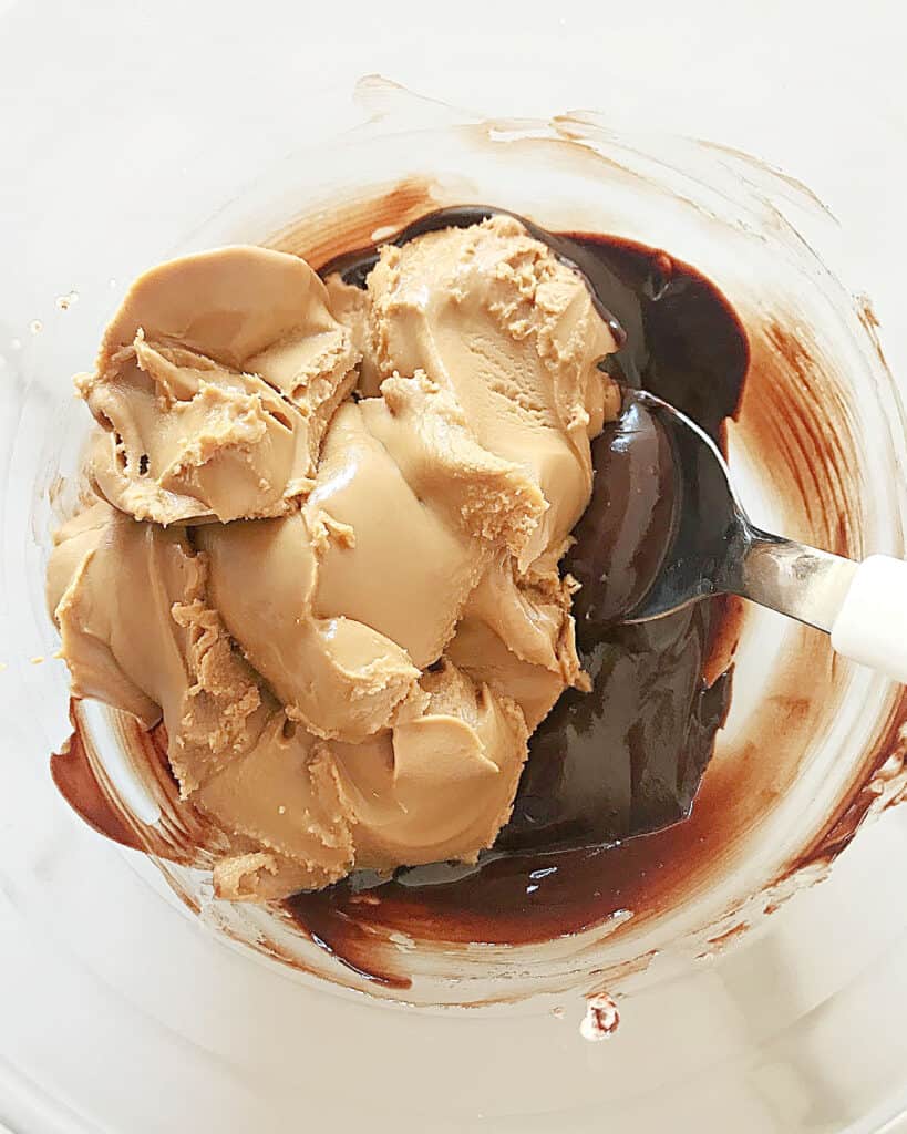 Melted chocolate and peanut butter in a glass bowl. Spoon inside. Top view.
