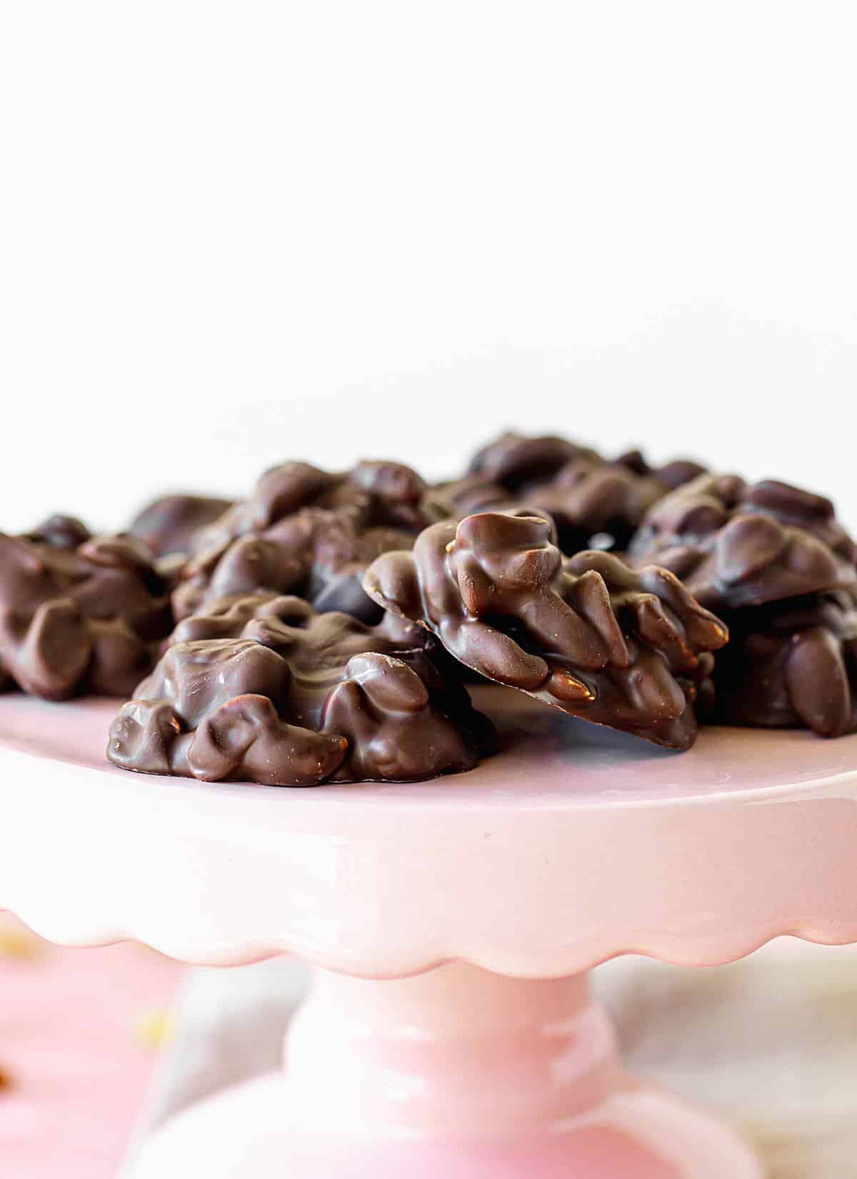 Close up of chocolate peanut clusters on a pink cake stand.