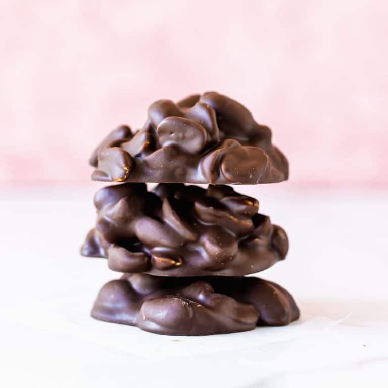 White and pink background with stack of three chocolate peanut clusters.