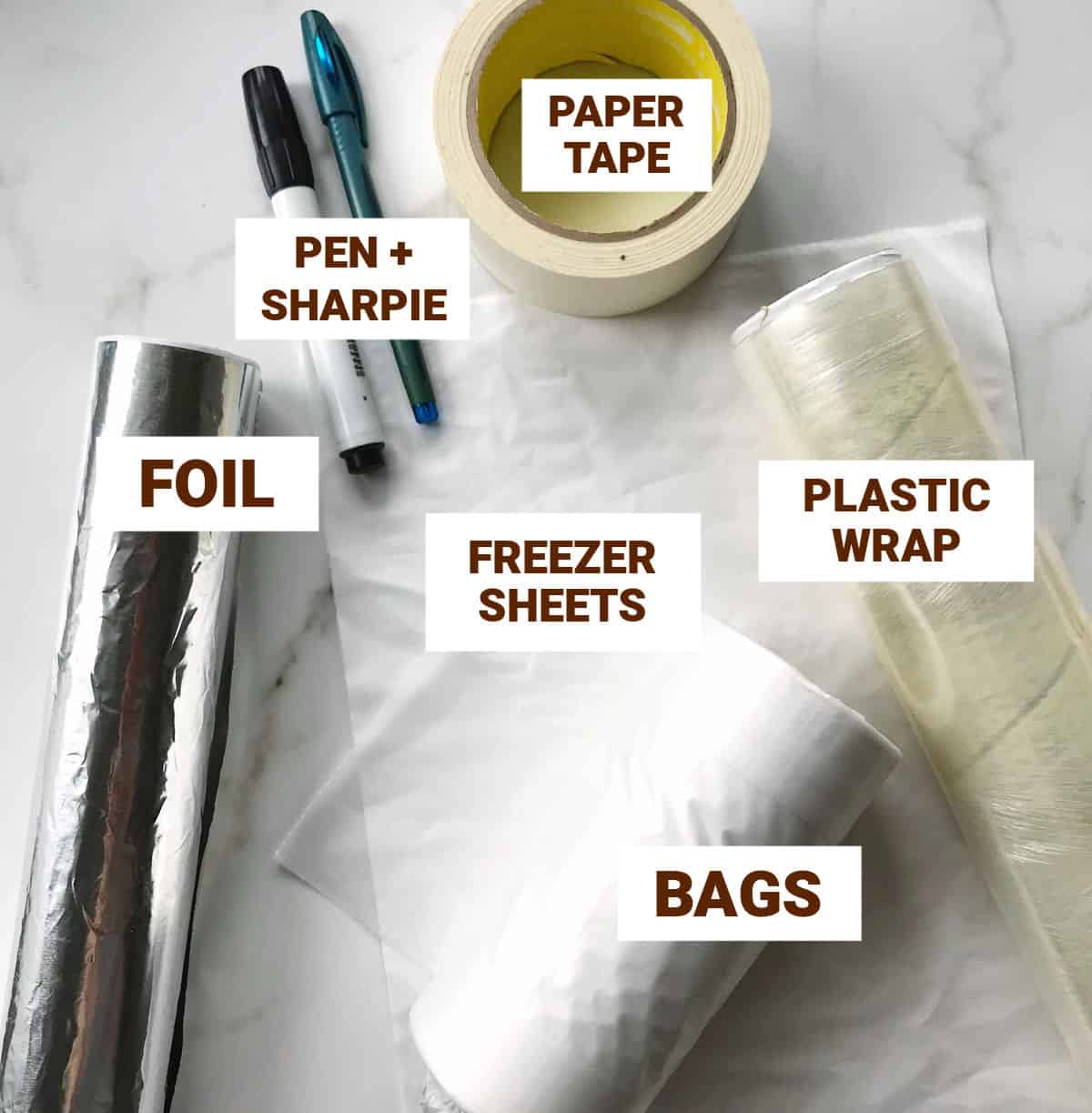 Pens, foil and plastic wrap, tape, bags on white marble surface