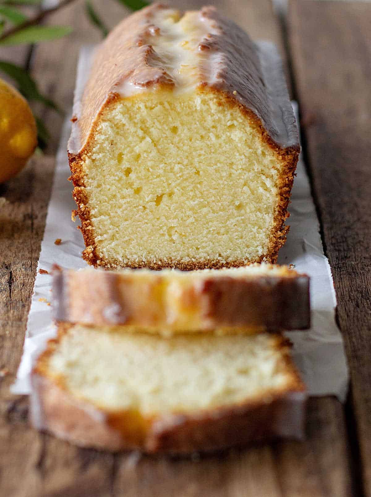 Wooden table with half lemon pound cake and slices