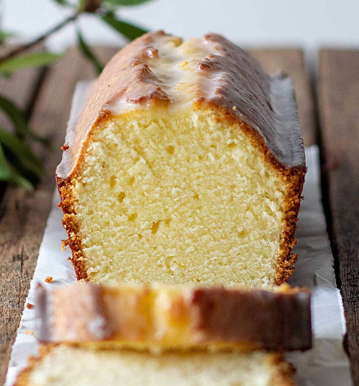 Cut lemon pound cake on wooden board, leaves around