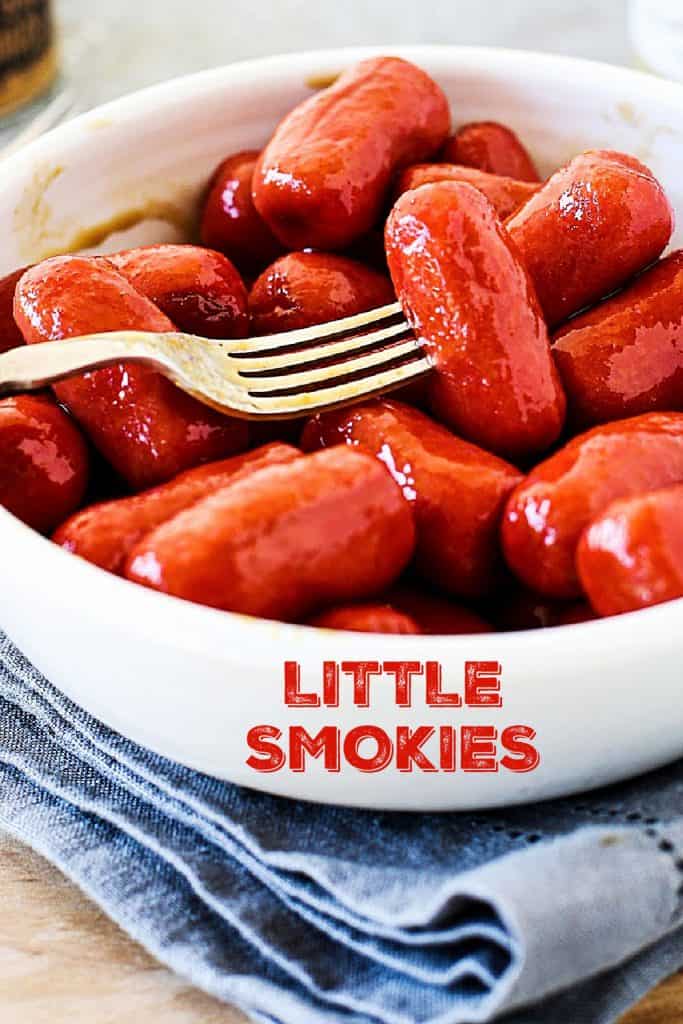 Close up of fork pinching little smokies in white bowl, blue napkin, red text overlay