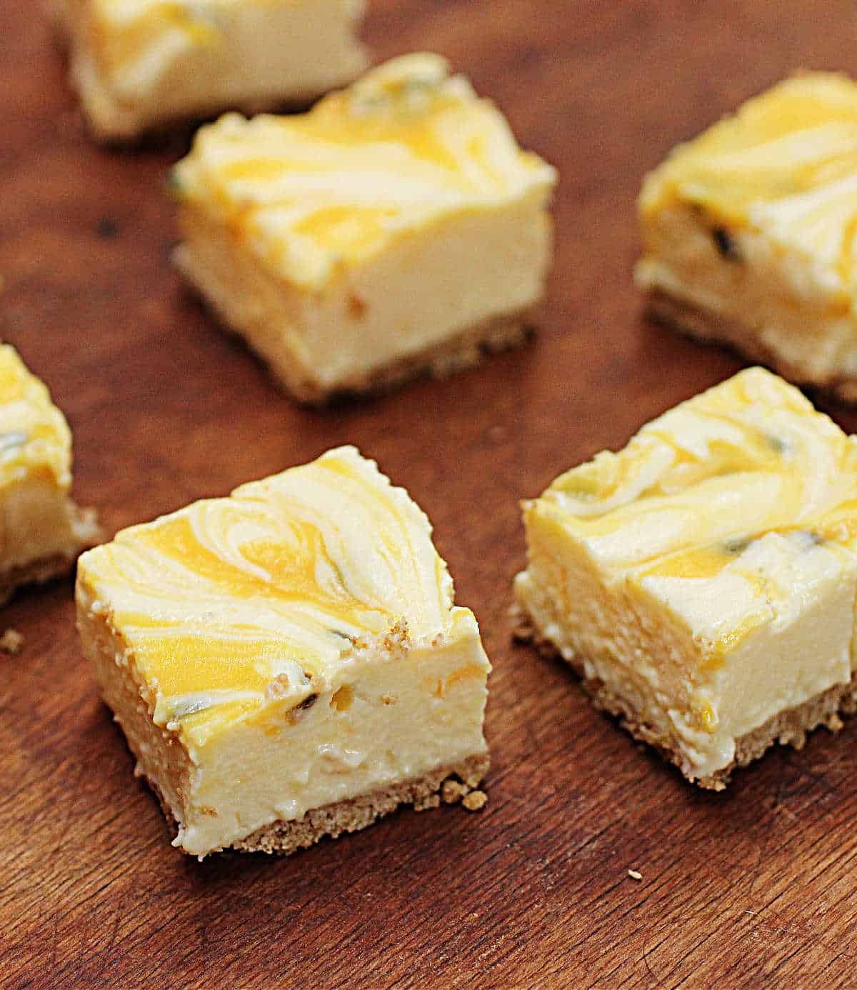 Squares of Passion fruit lemon no-bake cheesecake on wooden table