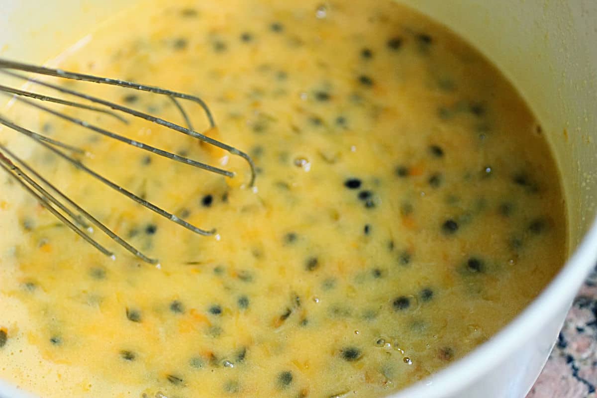 Whisking passion fruit curd in white bolw