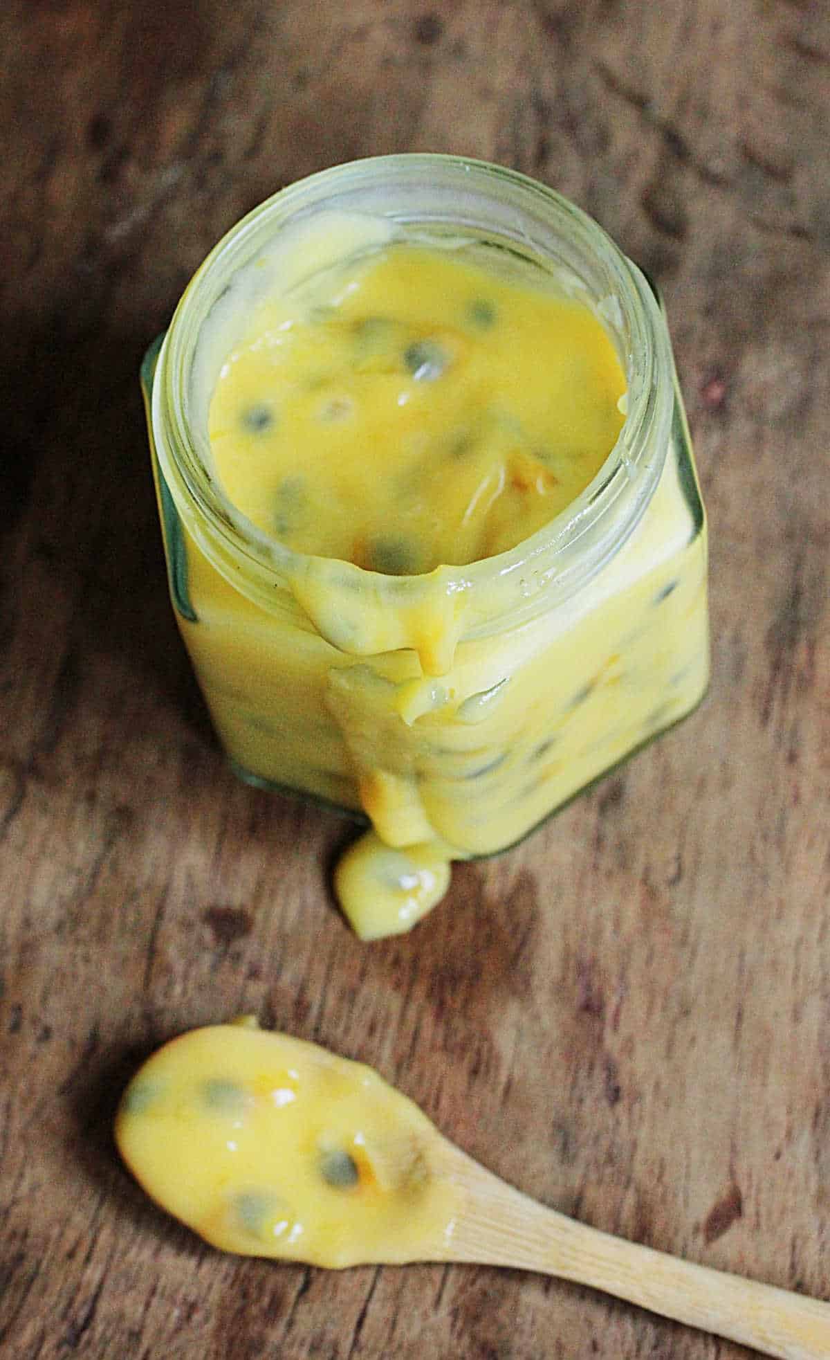 Top view of jar and spoon with passion fruit curd on a wooden table