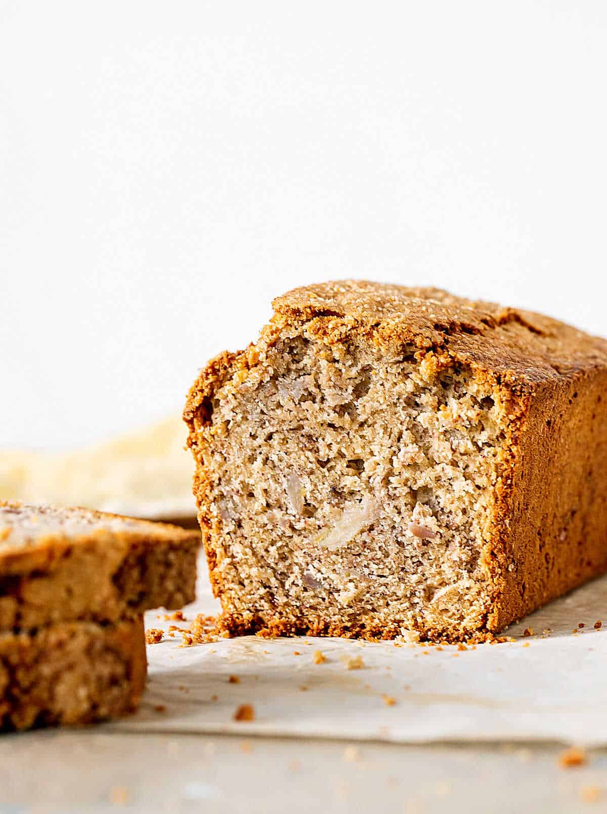 Half loaf of banana bread on beige surface and background