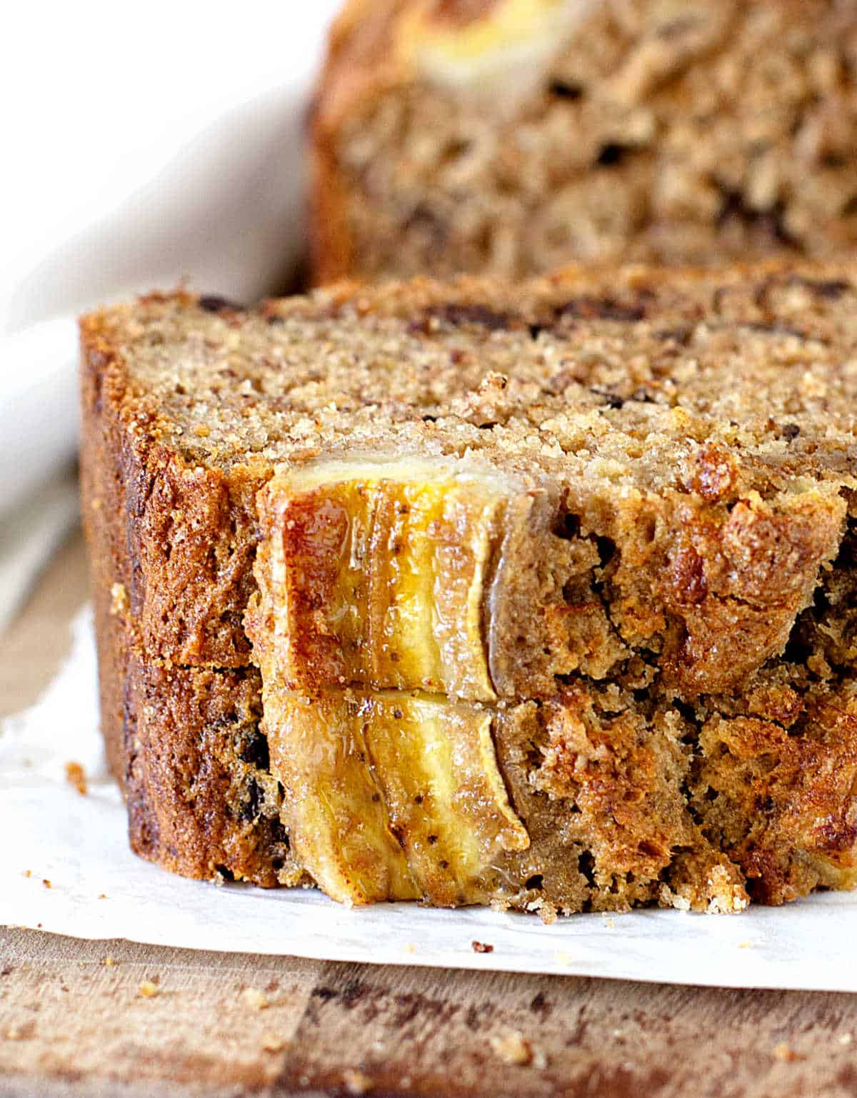 Two slices of banana bread stacked on a piece of white paper. 