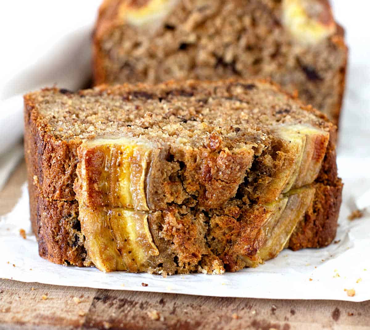 Two stacked slices of banana bread on white paper.