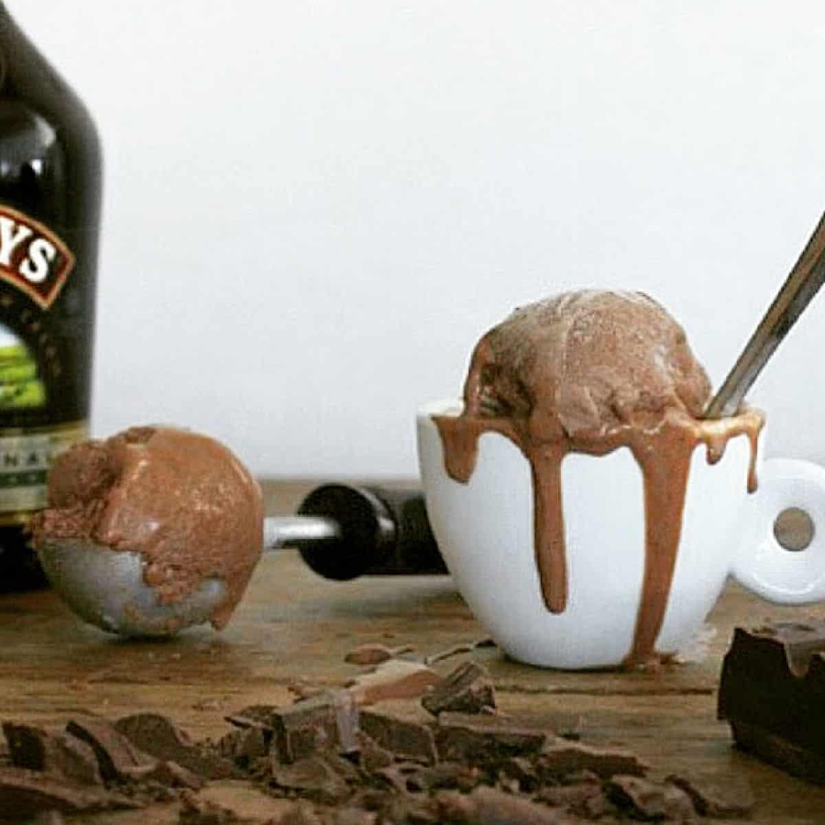 Wooden table with white cup and scoop of chocolate ice cream.