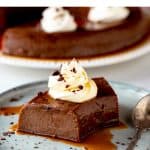 Slice of chocolate flan on grey plate with spoon; white brown text overlay