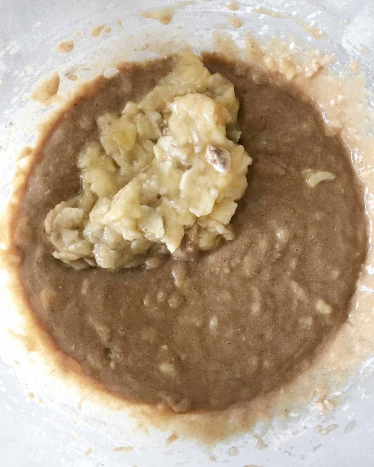 Banana chunks added to the batter in a glass bowl.