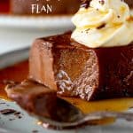 Close up of half eaten portion of chocolate flan with dollop of cream on grey plate; white text overlay