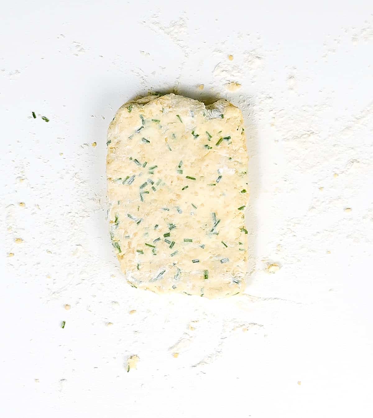 Final scone dough with chives on a floured white surface.
