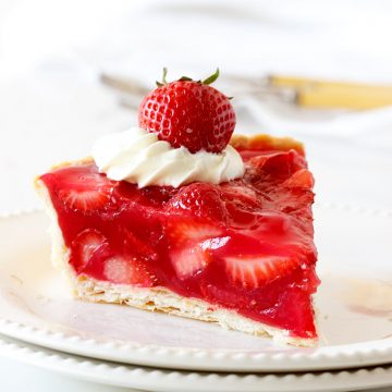 One slice of strawberry pie on two white plates