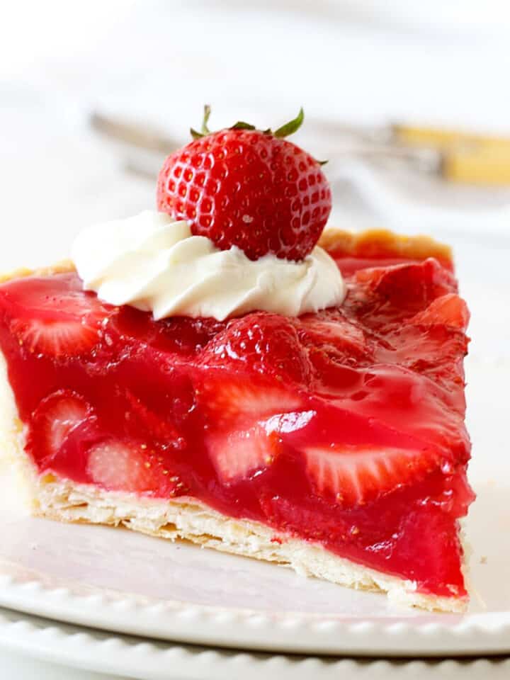 A slice of strawberry jello pie on a white plate. White background.