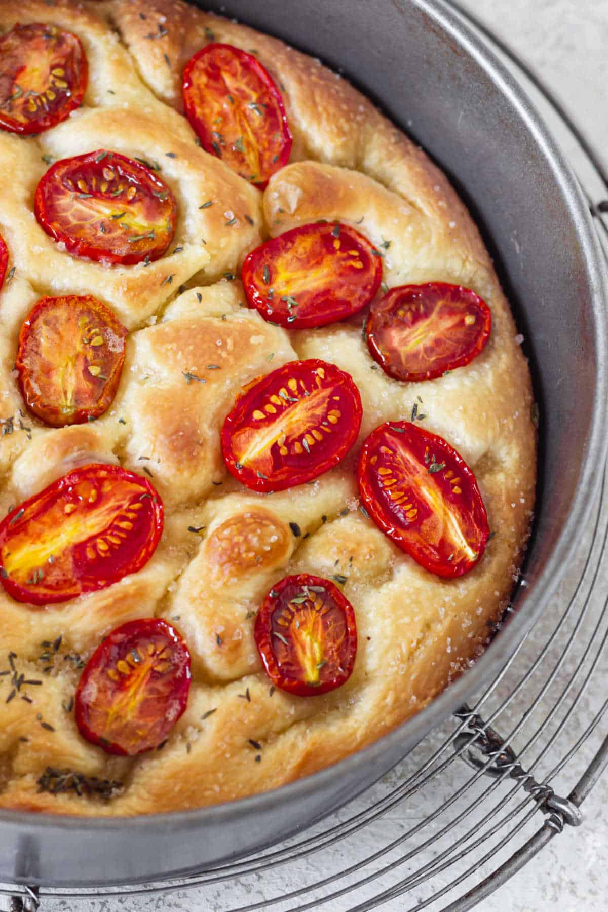 Partial view of baked tomato focaccia in metal pan on wire rack