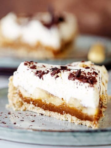 Close up slice of banoffee pie on grey plate, another serving in background