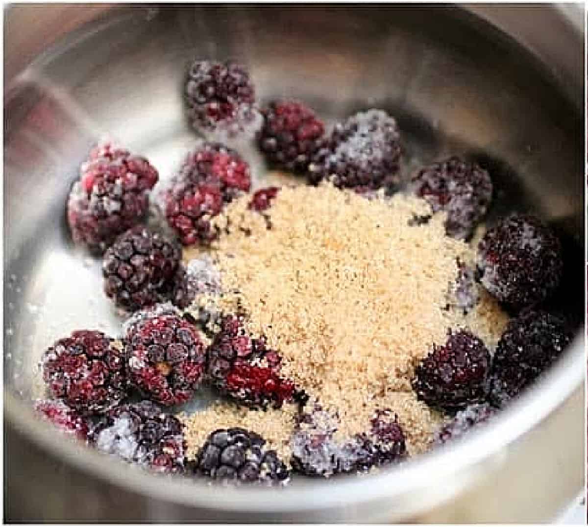 Metal saucepan with blackberries and brown sugar